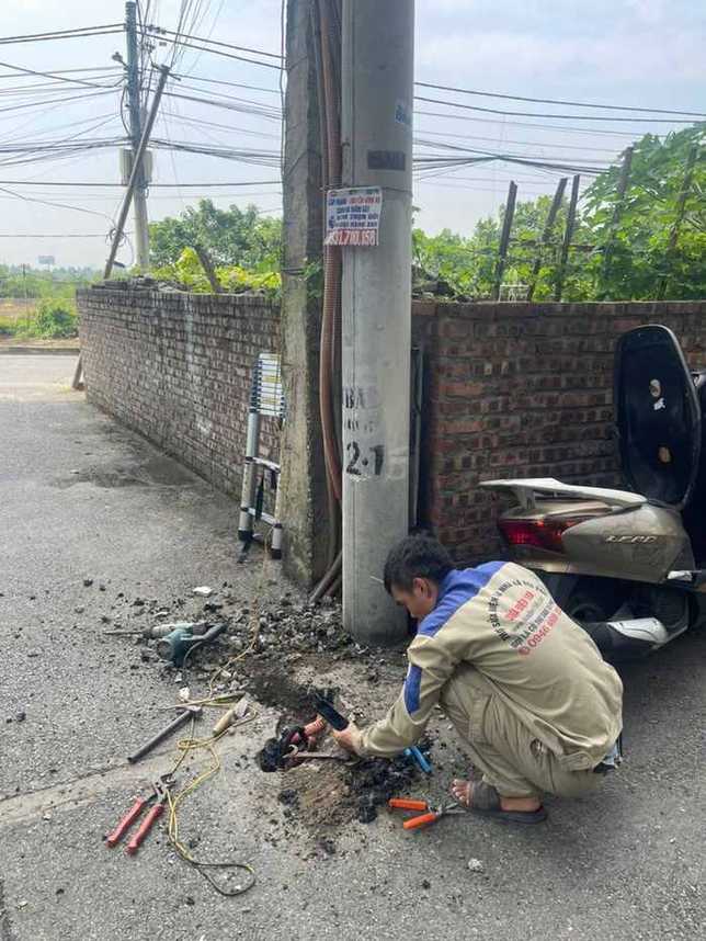 Thợ kiểm tra tuyến cáp ngầm bên cột điện trước khi đào sửa
