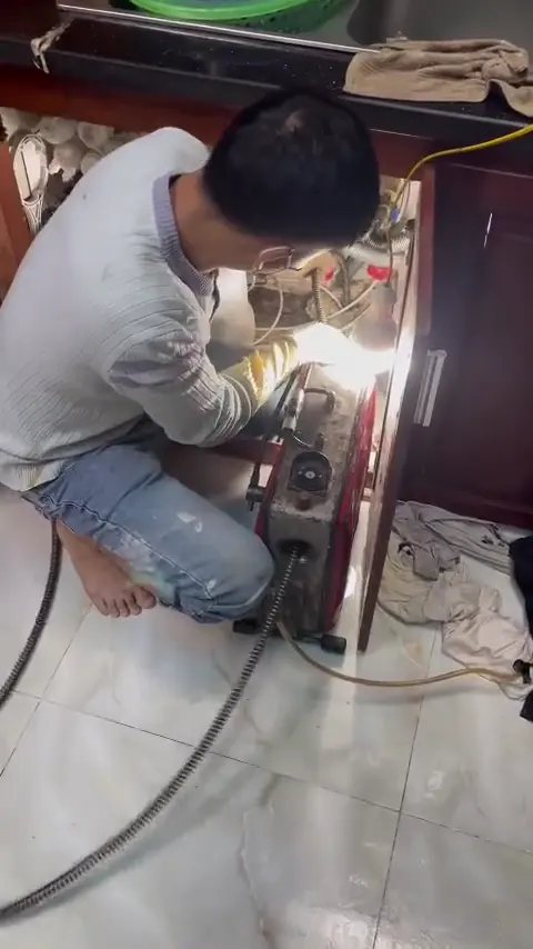 Kỹ thuật viên sử dụng máy xử lý đường ống dưới chậu rửa