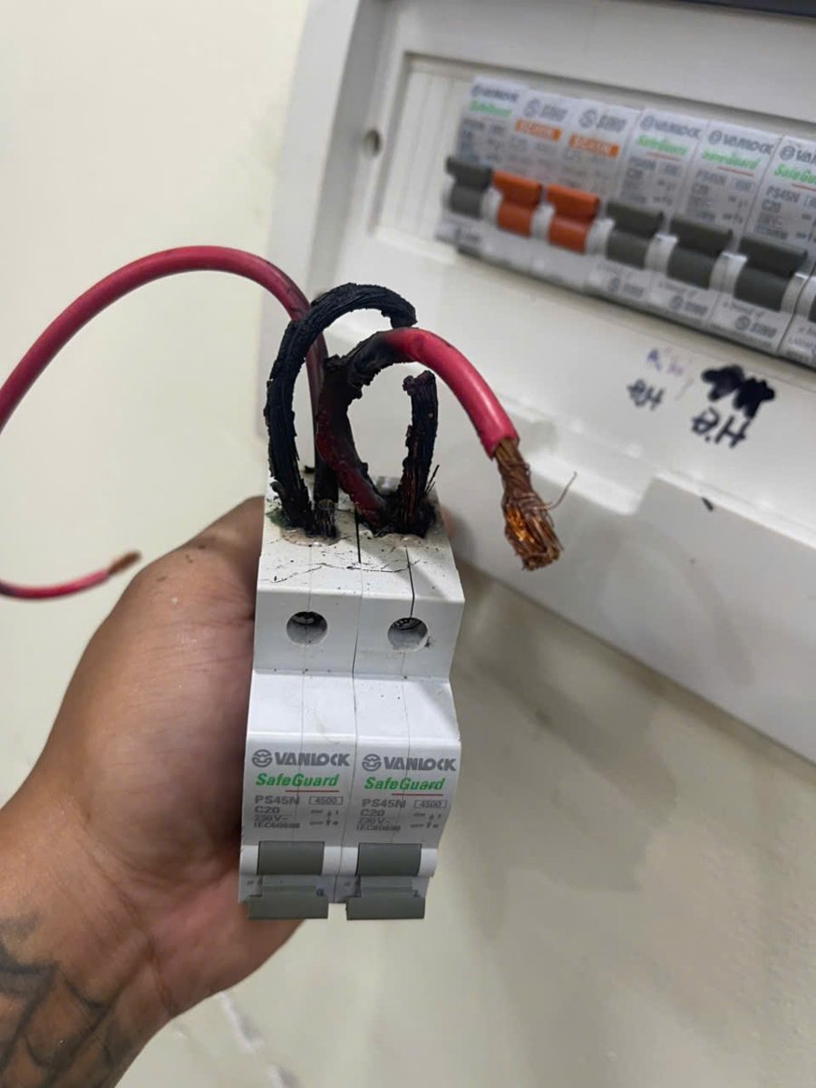 Aptomat tháo rời cùng các đầu dây, phía sau là tủ điện.